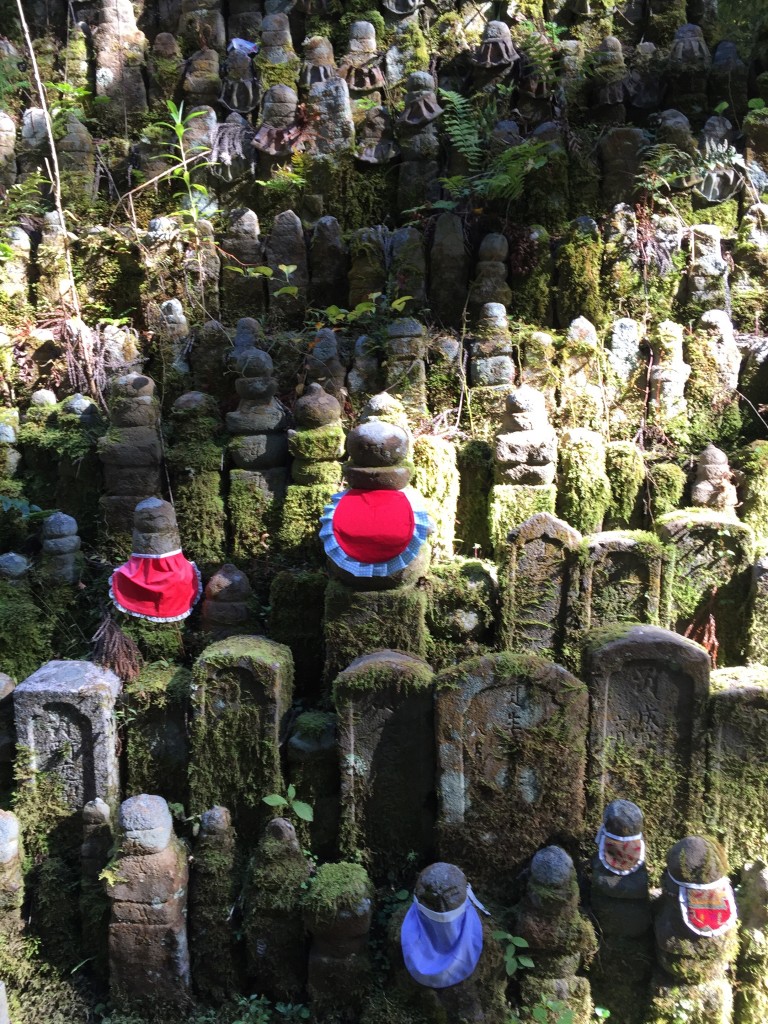The deity that you see here is named Jizo and he is the protector of travelers and children. It is said that children used to weat read bibs such as these and that dressing statues of the Jizo deity will bring merit in the afterlife.