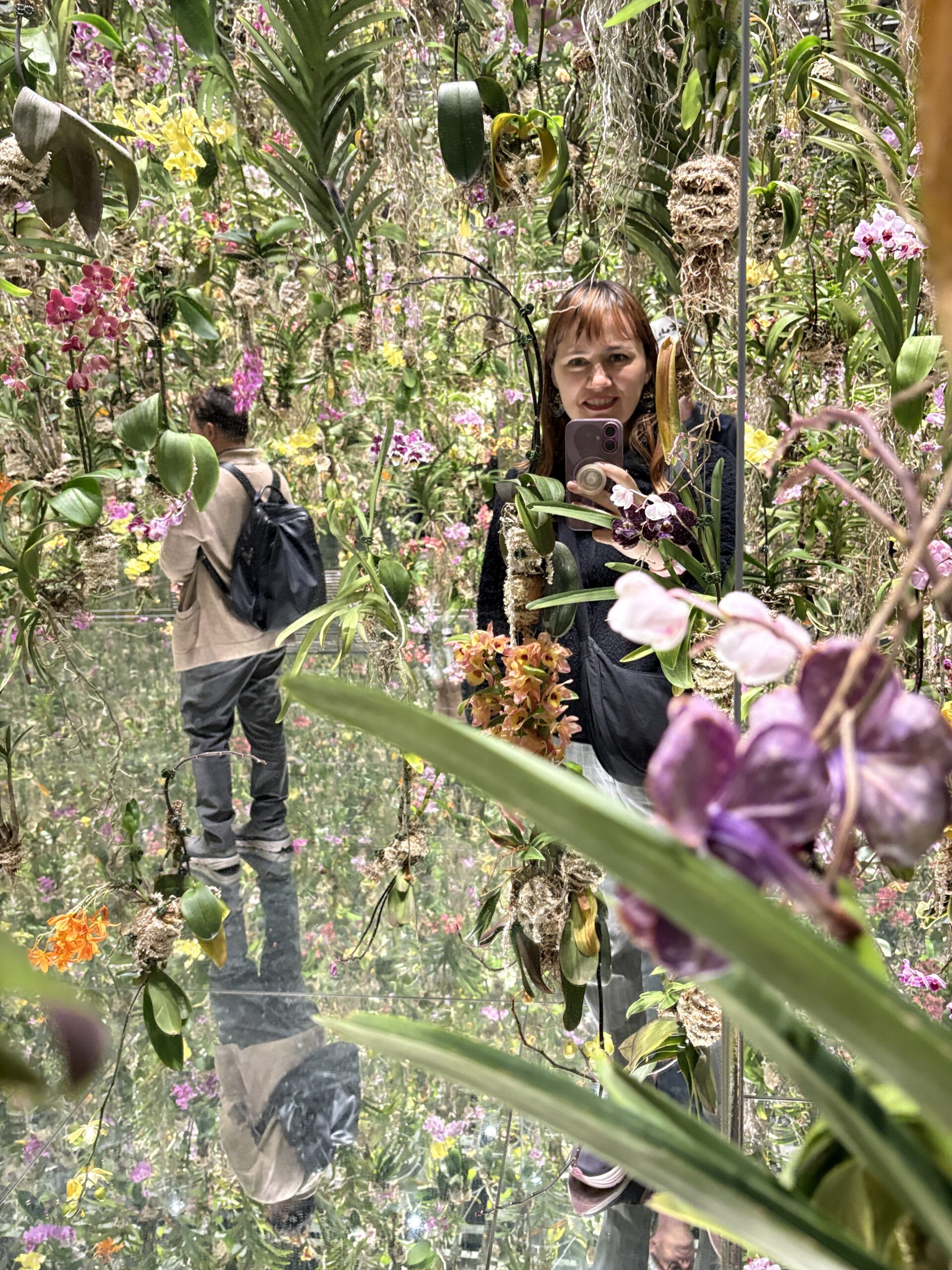Tokyo Becky surrounded by orchids in the Floating Flower Garden at teamLab Planets Tokyo